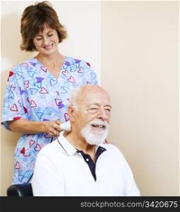 Senior man gets pain relief from a chiropractic nurse using an ultrasound machine.