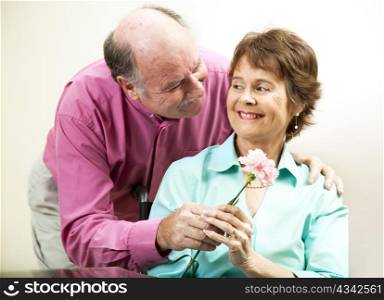 Senior man gives his beautiful wife a flower.