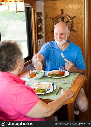 Senior man gives his wife a big thumbs up for the delicious dinner she made in their motor home.