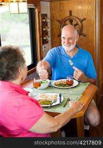 Senior man gives his wife a big thumbs up for the delicious dinner she made in their motor home.
