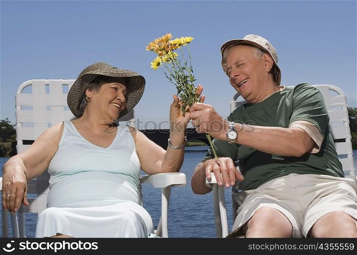 Senior man giving flowers to a senior woman and smiling