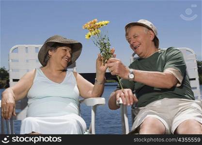 Senior man giving flowers to a senior woman and smiling