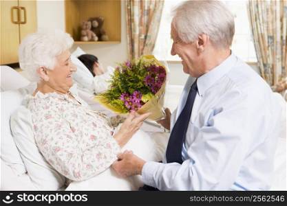 Senior Man Giving Flowers To His Wife In Hospital