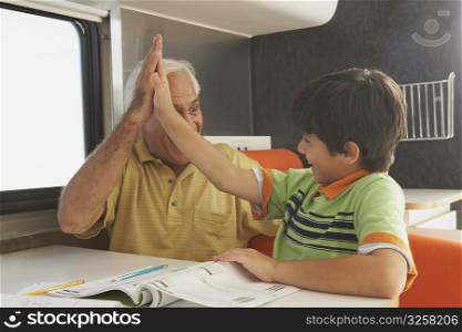 Senior man giving high-five to his grandson and smiling