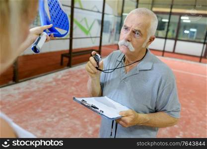 senior man giving tennis lesson