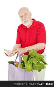 Senior man grocery shopping, shocked at the high cost of food. Isolated on white.