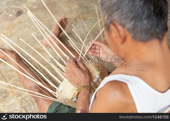 Senior man hands manually weaving bamboo.