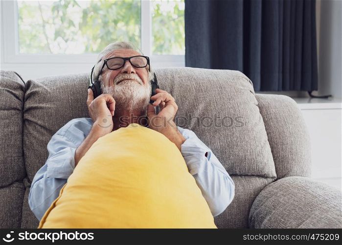 senior man happiness sitting on the sofa and listening music with headphone at living room for relaxing