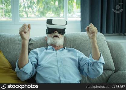 senior man happiness sitting on the sofa and playing game with VR headphone at living room for relaxing