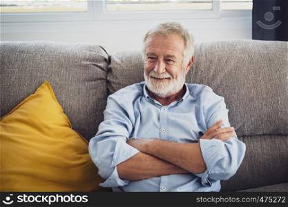 senior man happiness sitting on the sofa and smiling and thumbs up or point at living room for relaxing