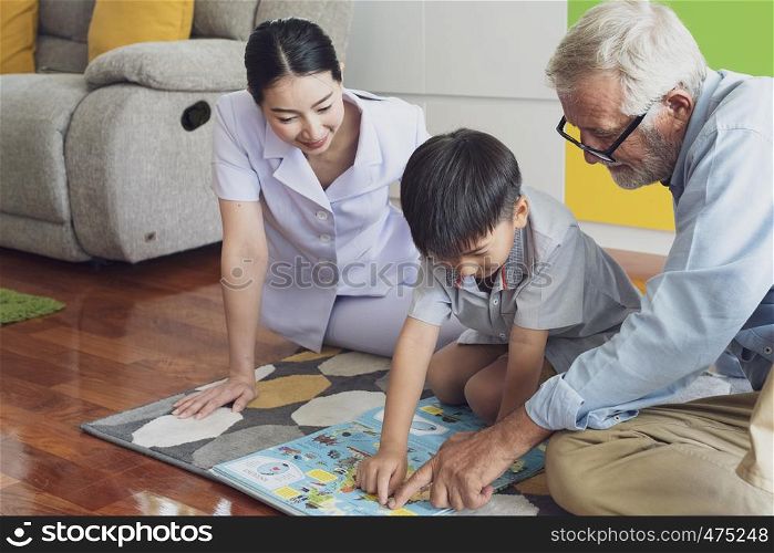 senior man happiness, smiling nurse and grandson are sitting on the floor and playing games at living room together