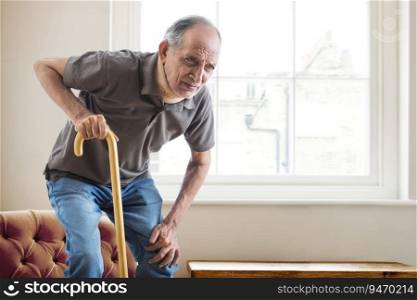 Senior man having a knee pain trying to stand up at home.  Health and fitness  