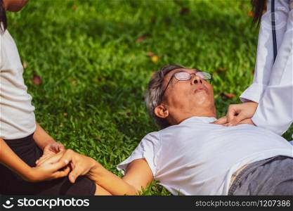 Senior man having chest pain or heart attack in the park. Old people elderly healthcare concept.. Doctor helping fainted senior man on the ground.
