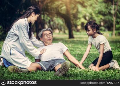 Senior man having chest pain or heart attack in the park. Old people elderly healthcare concept.. Doctor helping fainted senior man on the ground.