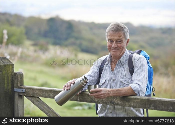 Senior Man Having Drink From Flask Whilst On Walk