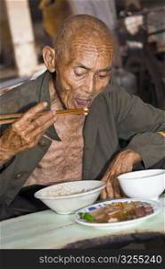 Senior man having food, XingPing, Yangshuo, Guangxi Province, China