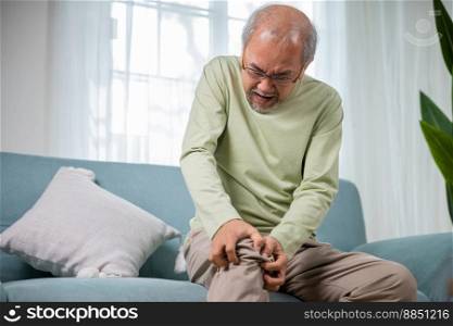 Senior man having painful knee pain after ligament surgery, senior man knee joint pain on sofa at home, Elderly old age pain after falling torn ligament, health problem, Healthcare and medical concept