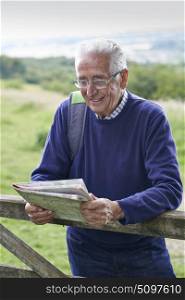 Senior Man Hiking In Countryside Looking At Map