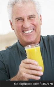 Senior Man Holding A Glass Of Fresh Orange Juice, Smiling At The Camera