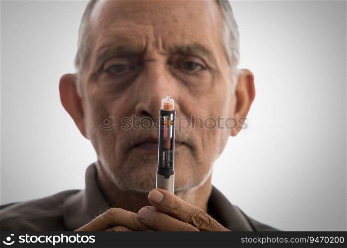 Senior man holding an insulin pen in hand.  Health and fitness  