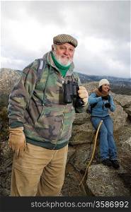 Senior man holding binoculars in mountains