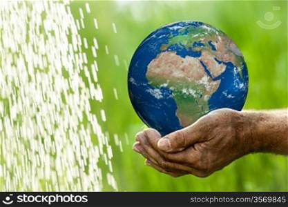 Senior man holding Earth in hands against green spring background. Elements of this image furnished by NASA