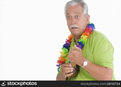 Senior man holding ukulele and looking surprised