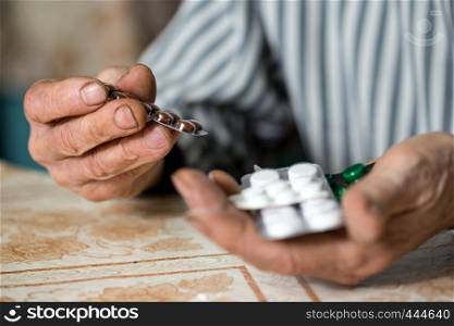 senior man holds a pill in his hands