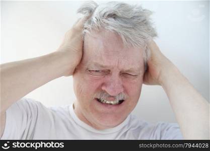Senior man holds his head in terrible pain.