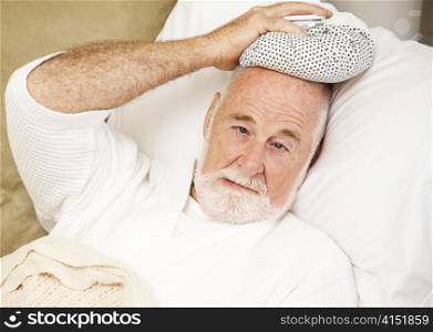 Senior man home sick with a cold, flu, or hangover.