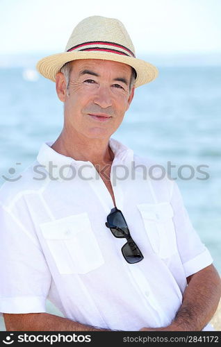 Senior man in a straw hat standing by the water