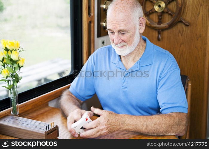 Senior man in his RV, shuffling cards to play cribbage. Motion blur on the cards.