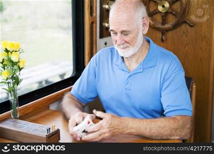 Senior man in his RV, shuffling cards to play cribbage. Motion blur on the cards.
