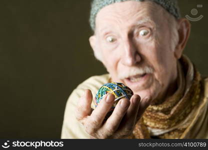 Senior man in knit cap contemplating a colorful rubber band ball