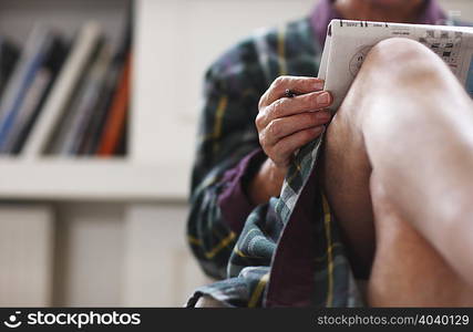 Senior man in robe relaxing with newspaper