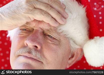 senior man in Santa hat with a headache
