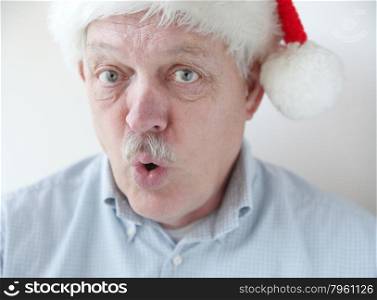 senior man in Santa hat with mischievous expression