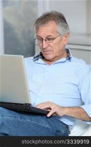 Senior man in sofa with laptop computer