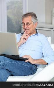Senior man in sofa with laptop computer
