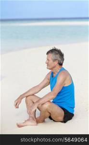 Senior Man In Sports Clothing Relaxing On Beautiful Beach