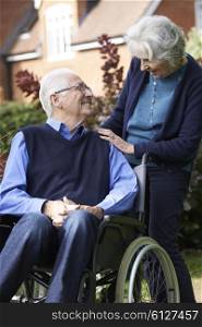 Senior Man In Wheelchair Being Pushed By Wife