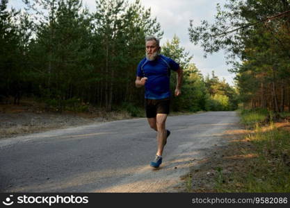 Senior man jogger performing exercise outside among countryside road. Healthy lifestyle and physical activity for wellness on retirement. Senior man jogger performing exercise outside among countryside road