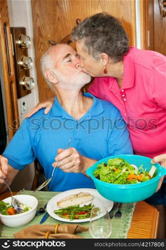 Senior man kisses his wife as she serves him dinner in their motor home.