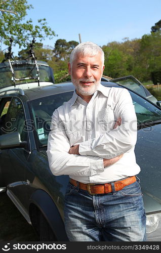 Senior man leaning on carhood