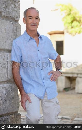 Senior man leaning on stone wall