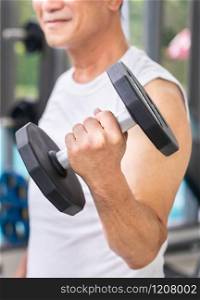 Senior man lifting dumbbell in fitness gym. Senior healthy lifestyle.. Senior man lifting dumbbell in fitness gym.