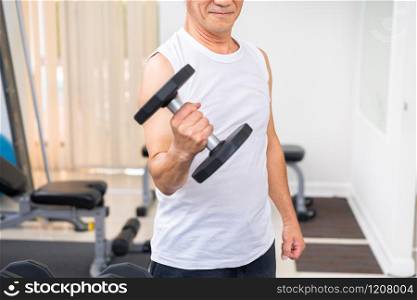 Senior man lifting dumbbell in fitness gym. Senior healthy lifestyle.. Senior man lifting dumbbell in fitness gym.