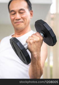 Senior man lifting dumbbell in fitness gym. Senior healthy lifestyle.