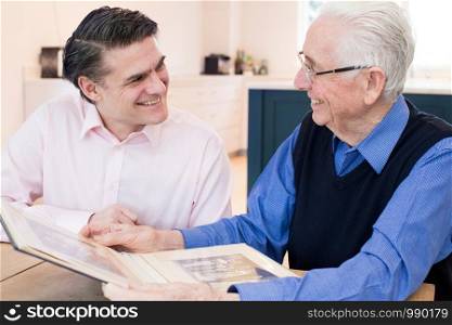 Senior Man Looking At Photo Album With Adult Son