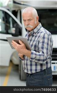 senior man looking at tablet in garage